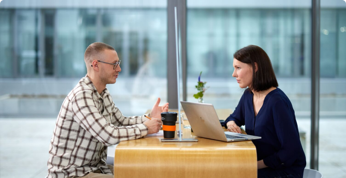Two Healthineers sitting at a table in the office and having a conversation