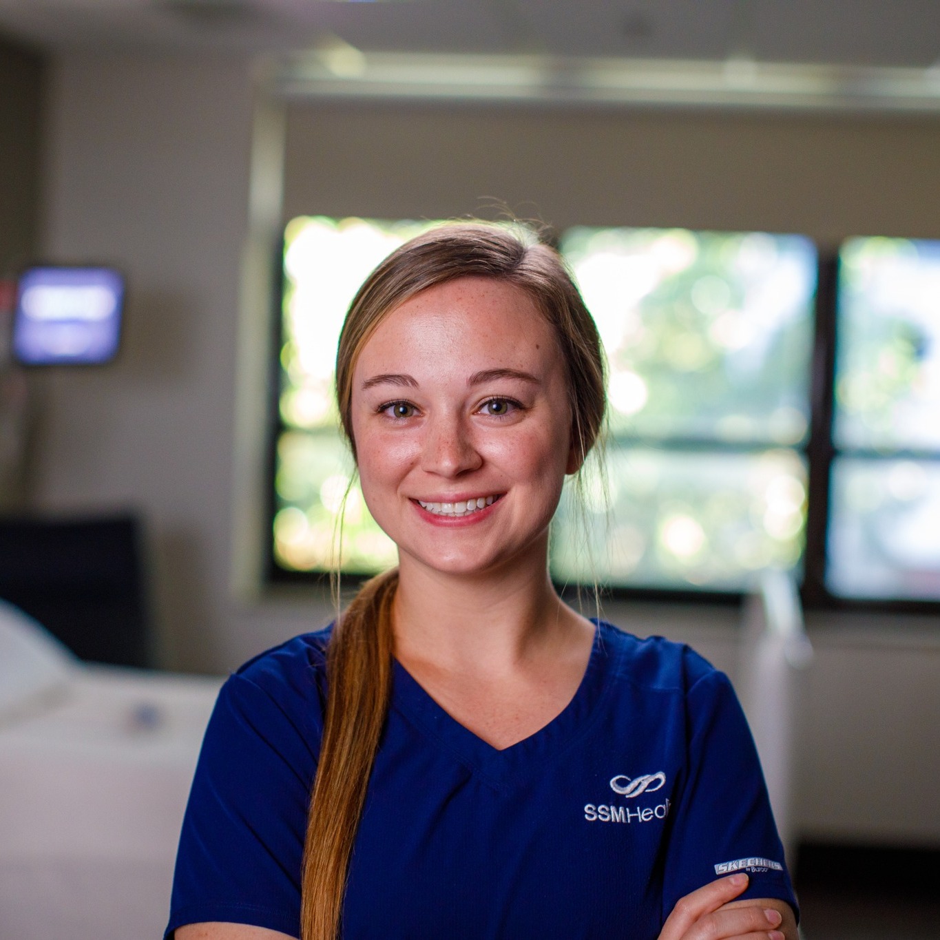 Nurse in scrubs smiling at camera