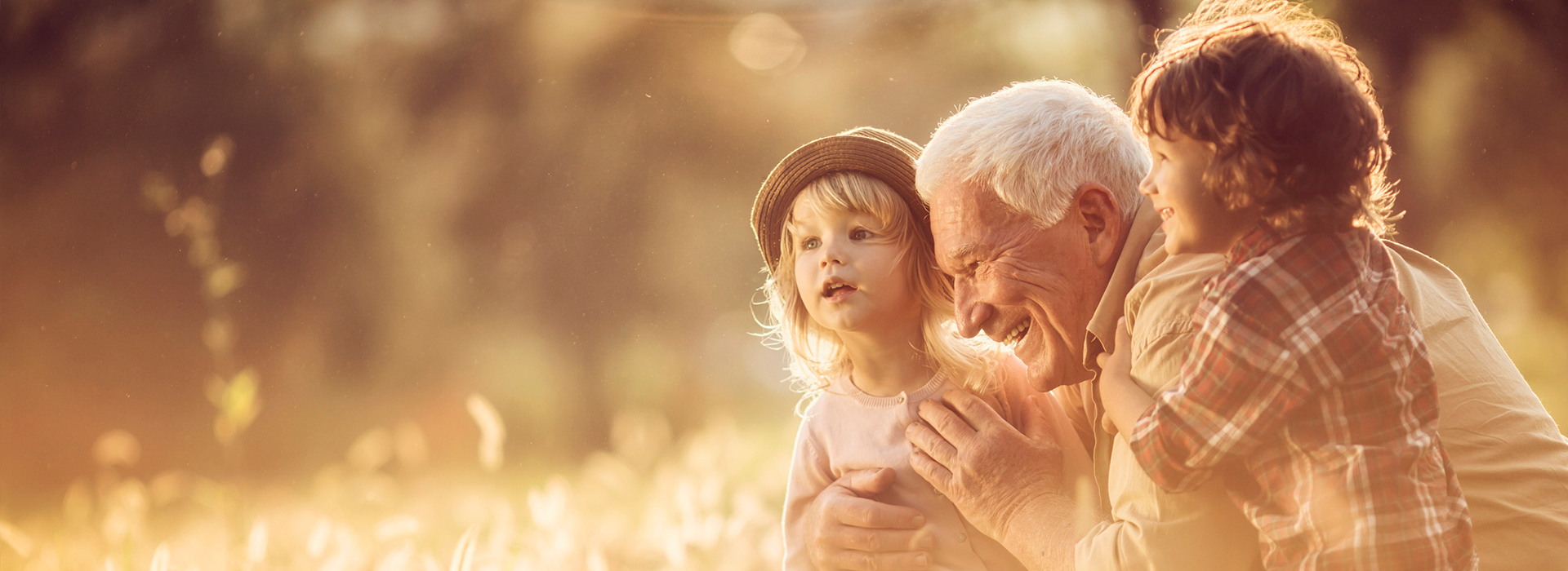 image of a happy male senior having fun with his two grandchildren in an outdoor setting