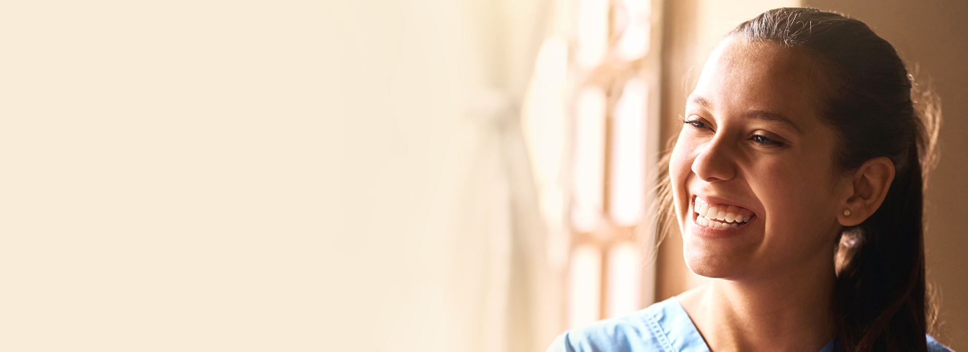image of a nurse with a cheerful smile beside the window