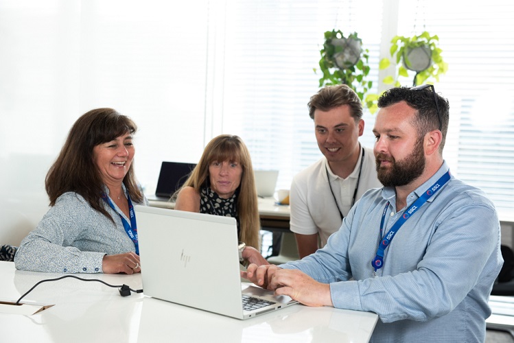 A team gathered around a laptop