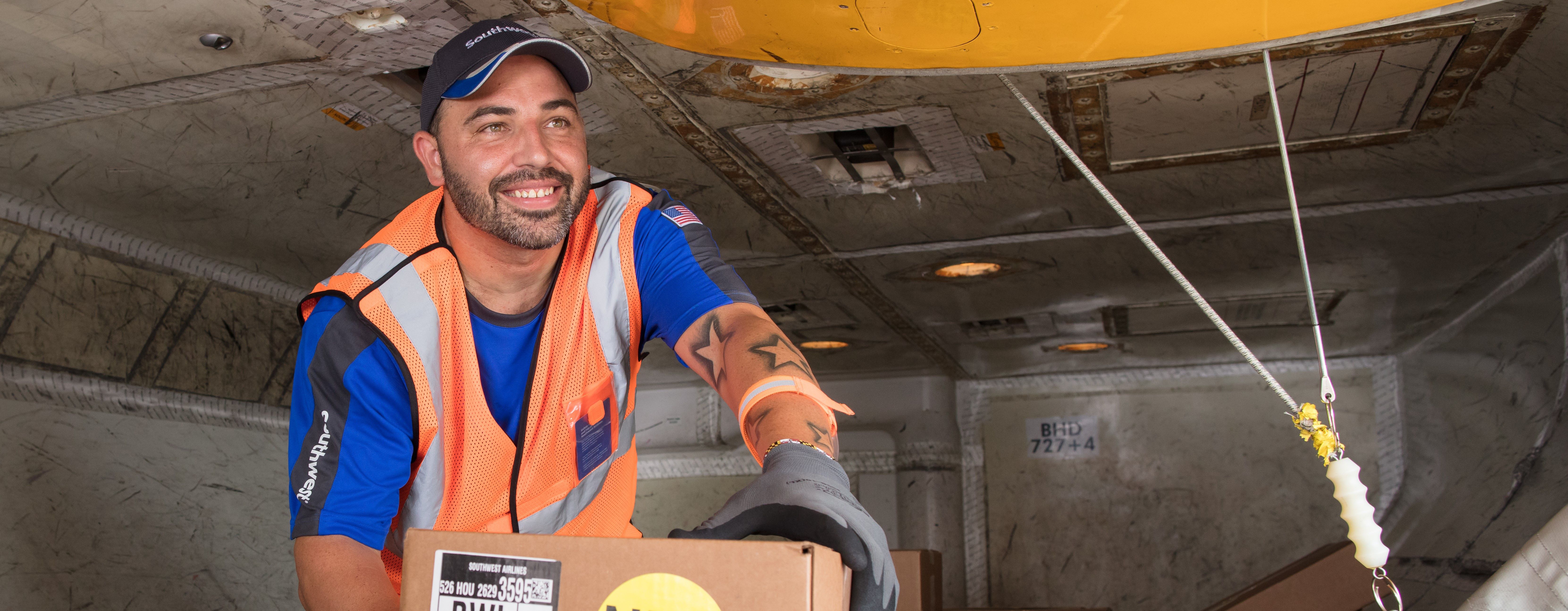 Southwest Employee smiling with a package in the bin of a plane