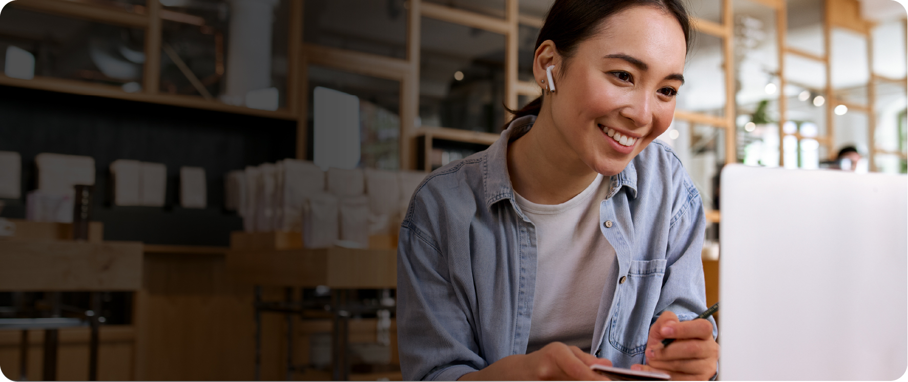 Smiling woman with earbud in looking at a laptop