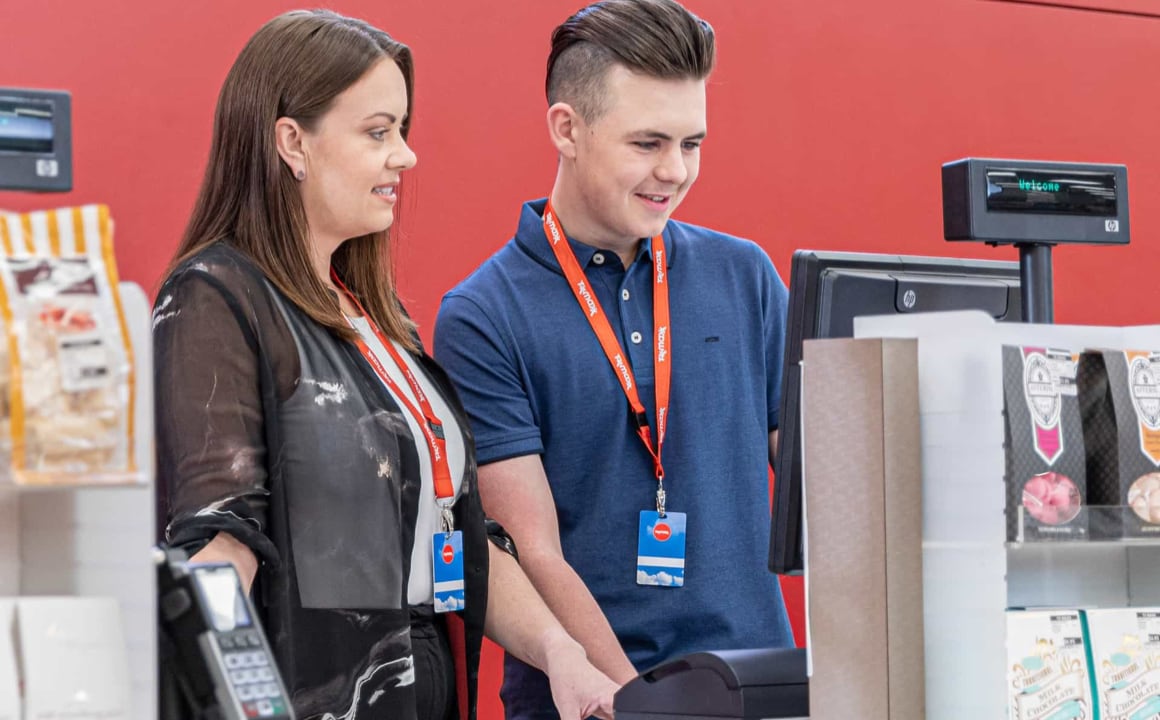 Manager of a TJX store smiling and supervising colleague