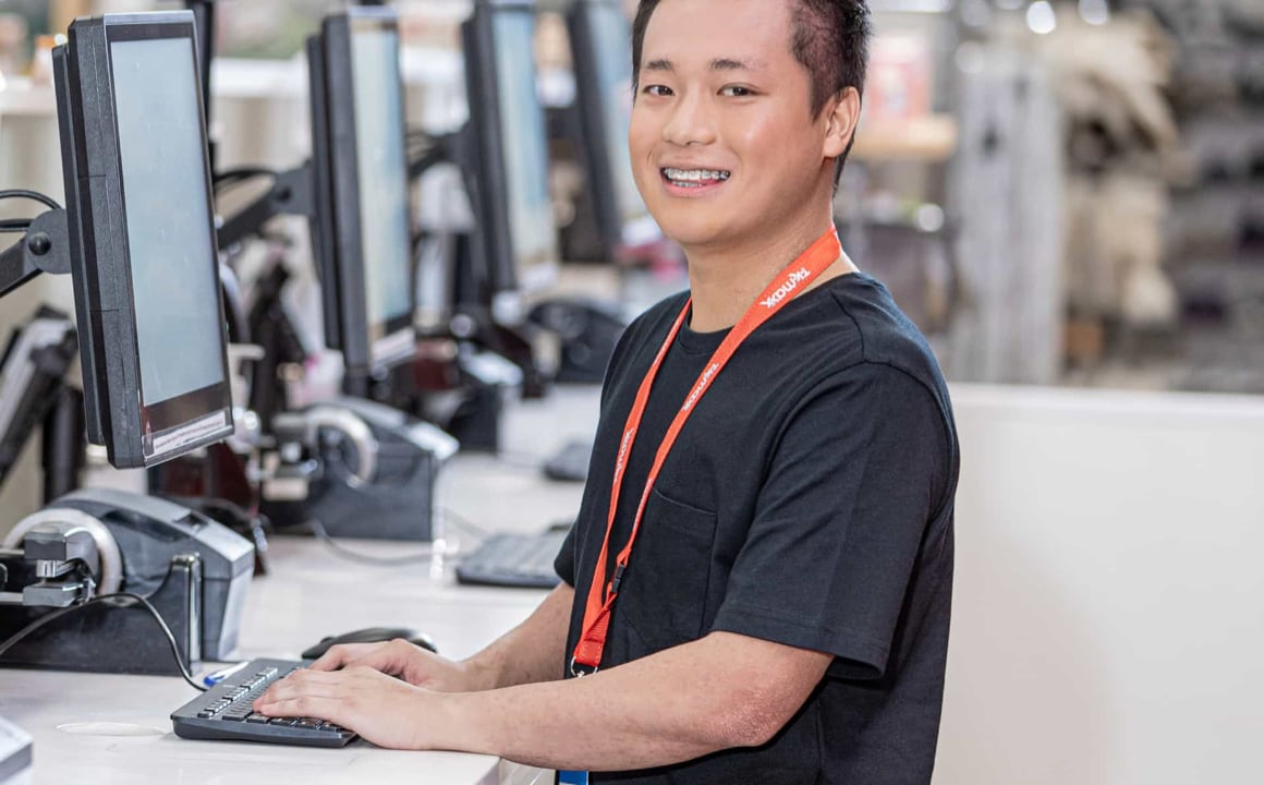 TJX professional working on the computer and smiling at camera