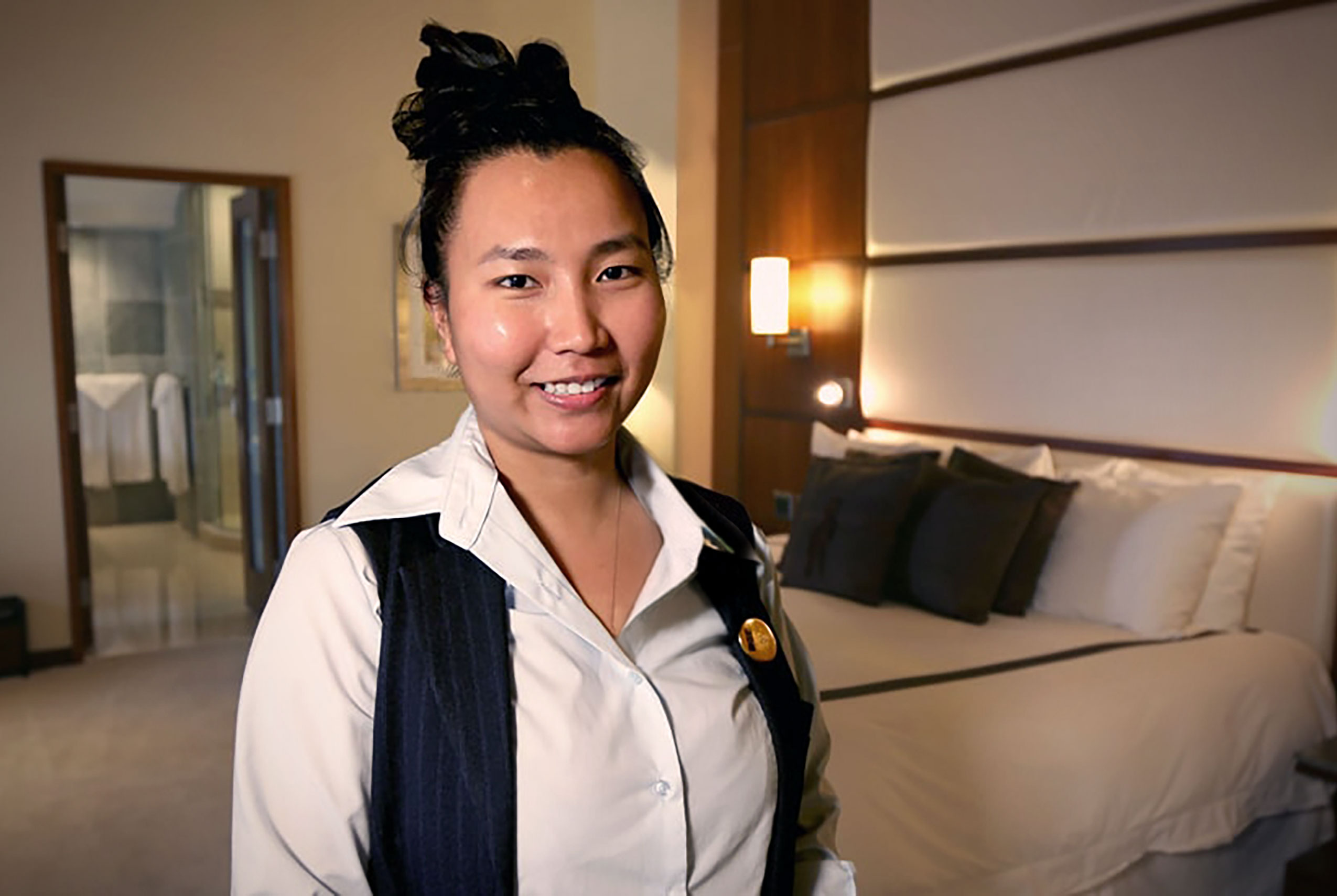 A team member smiling for the camera while working in one of the hotel rooms run by Turning Stone Enterprises. 