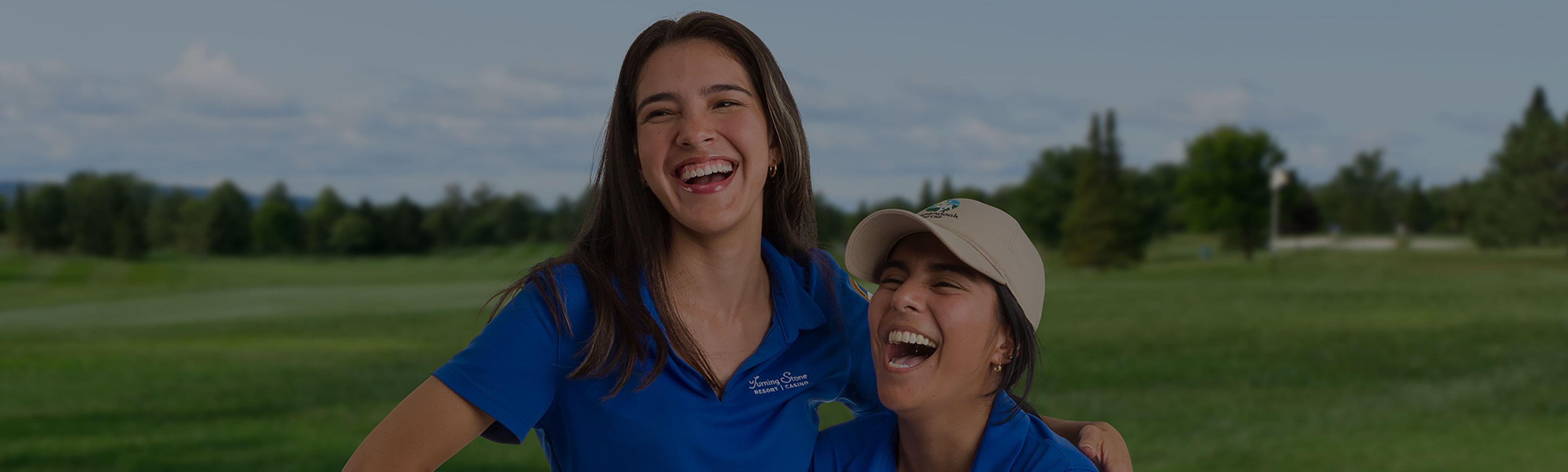 Two team members are laughing and enjoying a moment together on the golf course. 