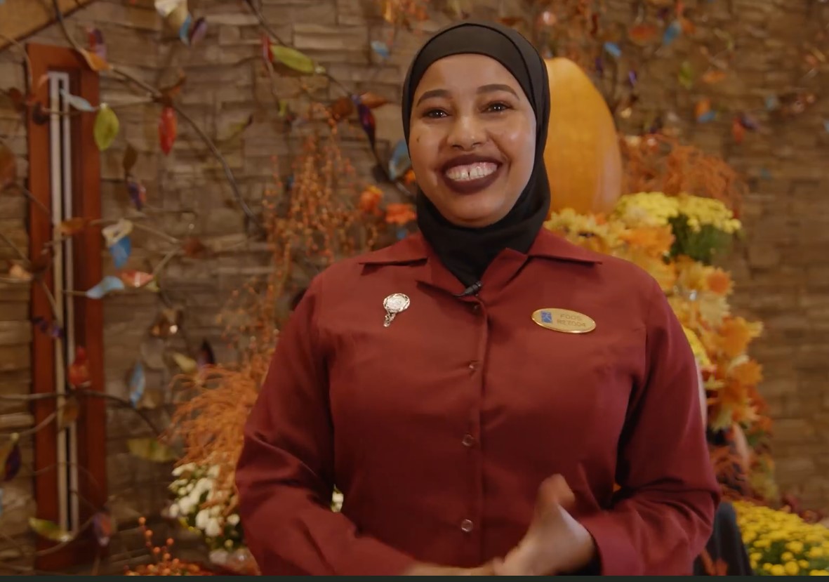 Team member smiling for the camera with yellow and orange flowers in the background. 