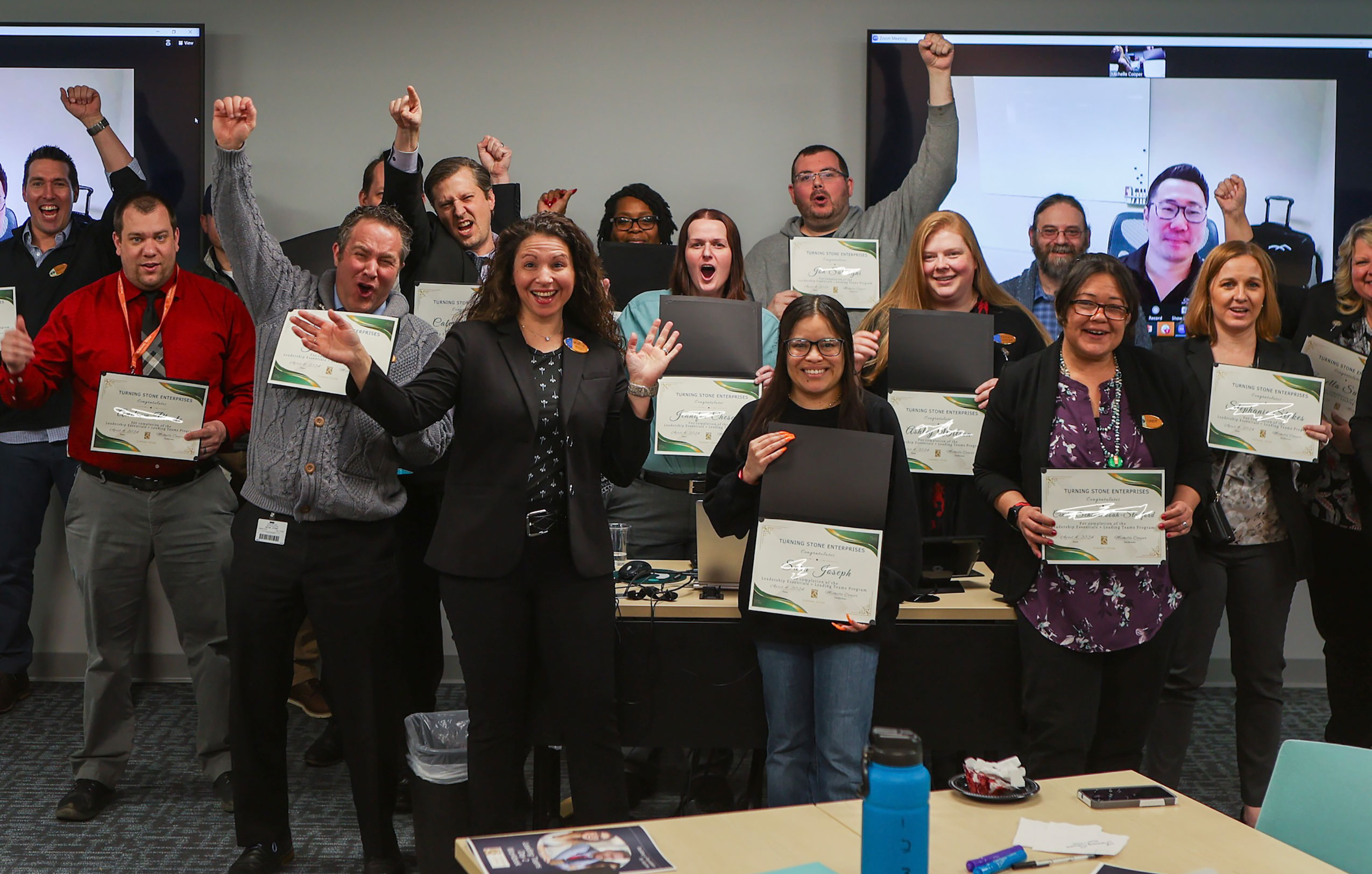 Team members holding certificates and cheering for the camera. 