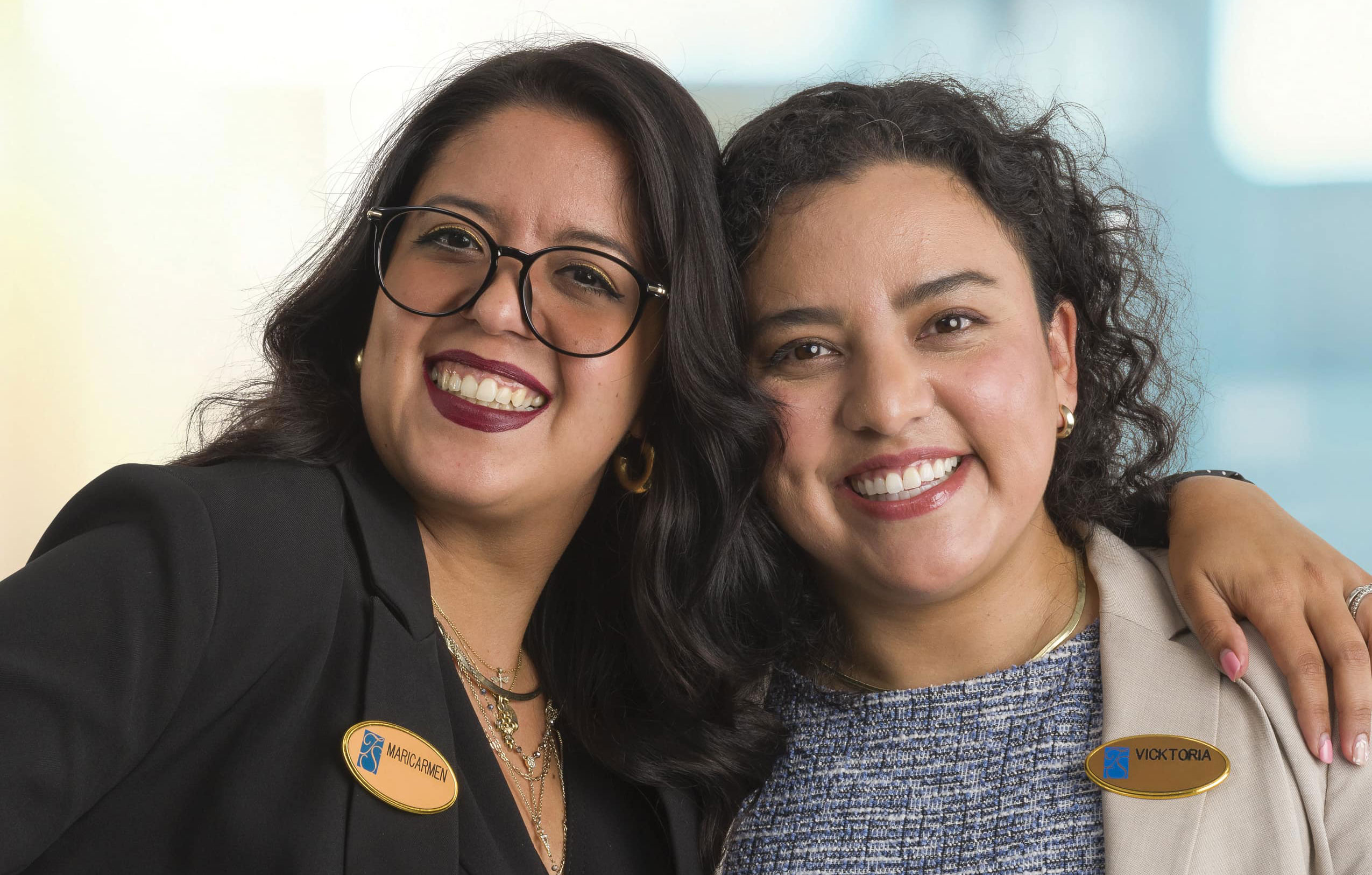 Two team members smiling for the camera. One has their arm around the other's shoulders. 