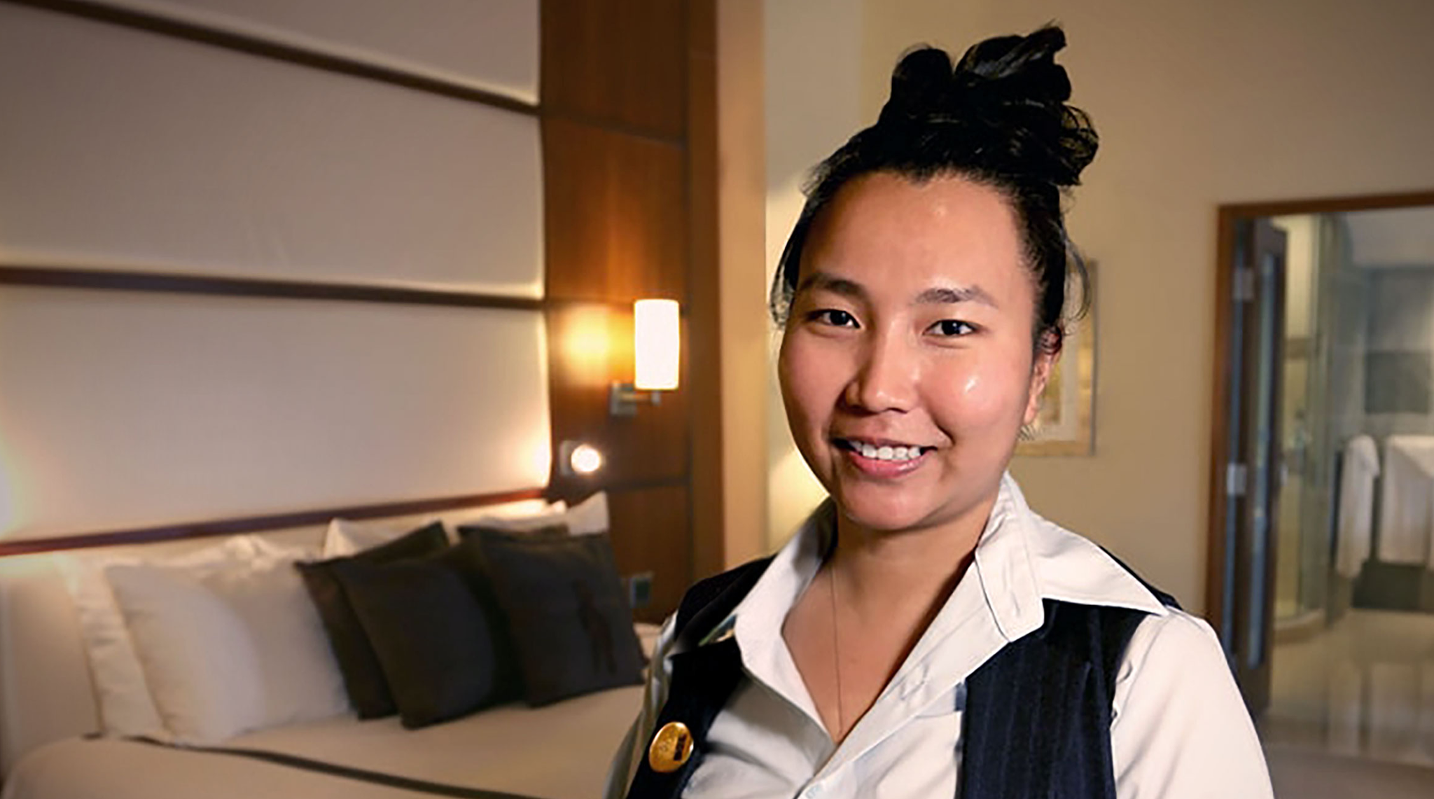 A team member smiling for the camera while working in one of the hotel rooms run by Turning Stone Enterprises. 