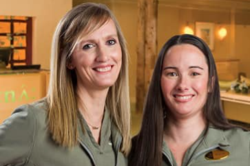 Two massage therapy team members smiling for the camera inside a spa.