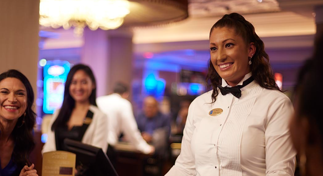 Dealer is smiling and interacting with guests at a casino table. 