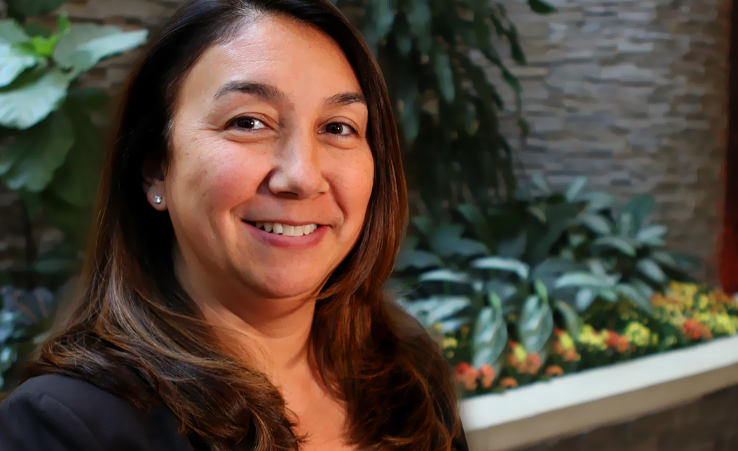 A team member smiling for the camera in front of plants.