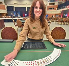 A team member spreading cards out on a game table on the casino floor. 