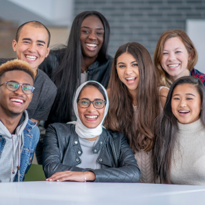 Varios compañeros de trabajo de diferentes orígenes sonriendo en un ambiente de oficina.
