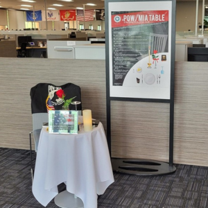 Empty table and chair at a TD SYNNEX office, with sign that says "POW/MIA Table"