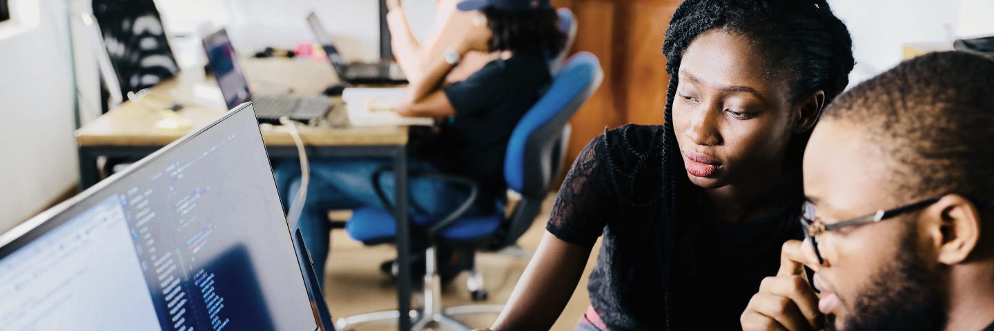 2 collègues révisant du code sur un moniteur dans un espace de bureau.