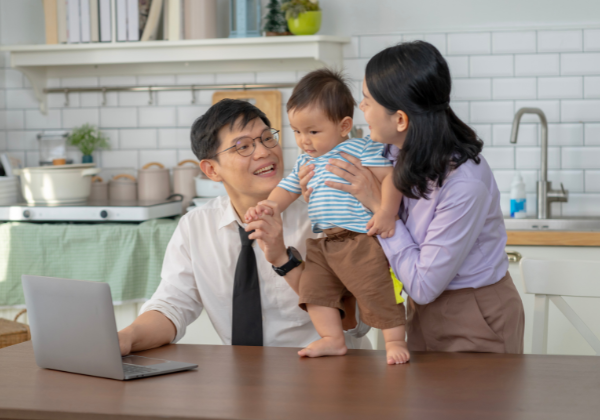 One man holding a toddler in his arms while another man shakes the toddler's hand.