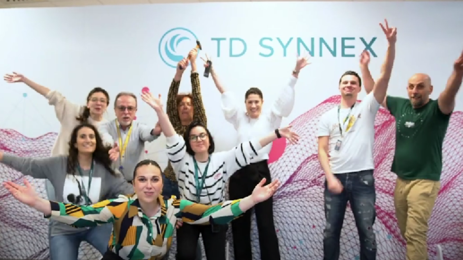 TD SYNNEX employees stretching their arms out and holding peace signs with the TD SYNNEX logo in the background