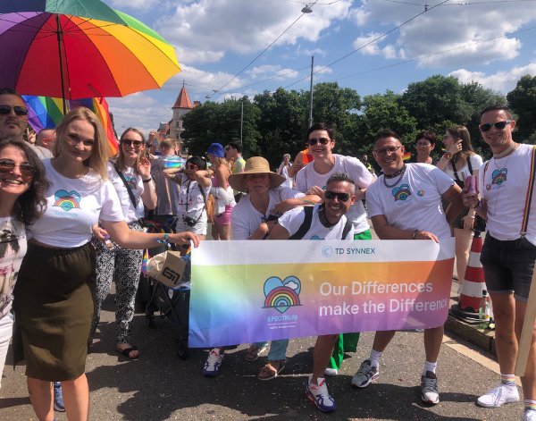 Many coworkers holding and posing near a banner that says "TD SYNNEX spectrum - Our differences make the difference"