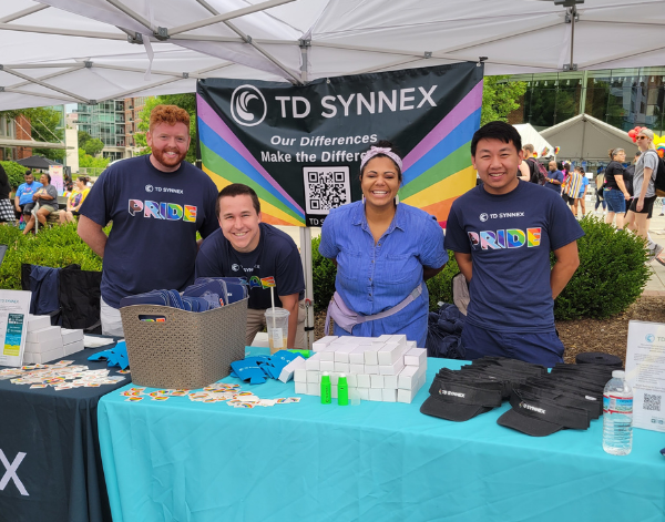 4 people standing in pride shirts at a TD SYNNEX pride event booth.