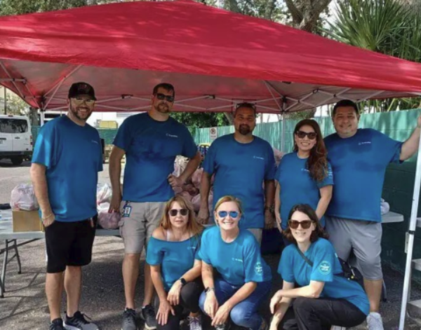 8 team members posing under a canopy.