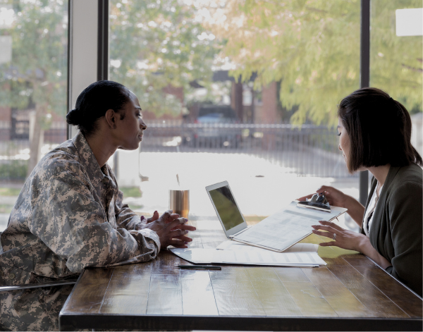 Conversation between a woman in business clothes and a woman in military uniform at a coffee shop.