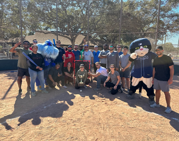 Group of 20 employees posing together on a baseball pitch.