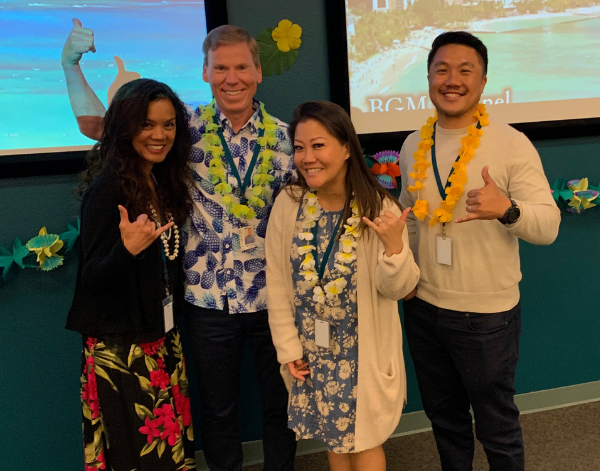 4 team members posing in leis at a work event.