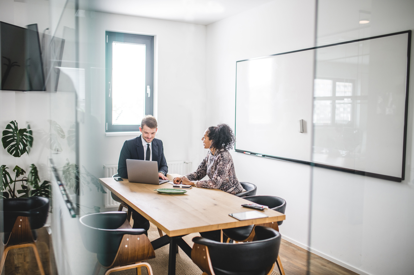 Two business people at a table looking at a laptop