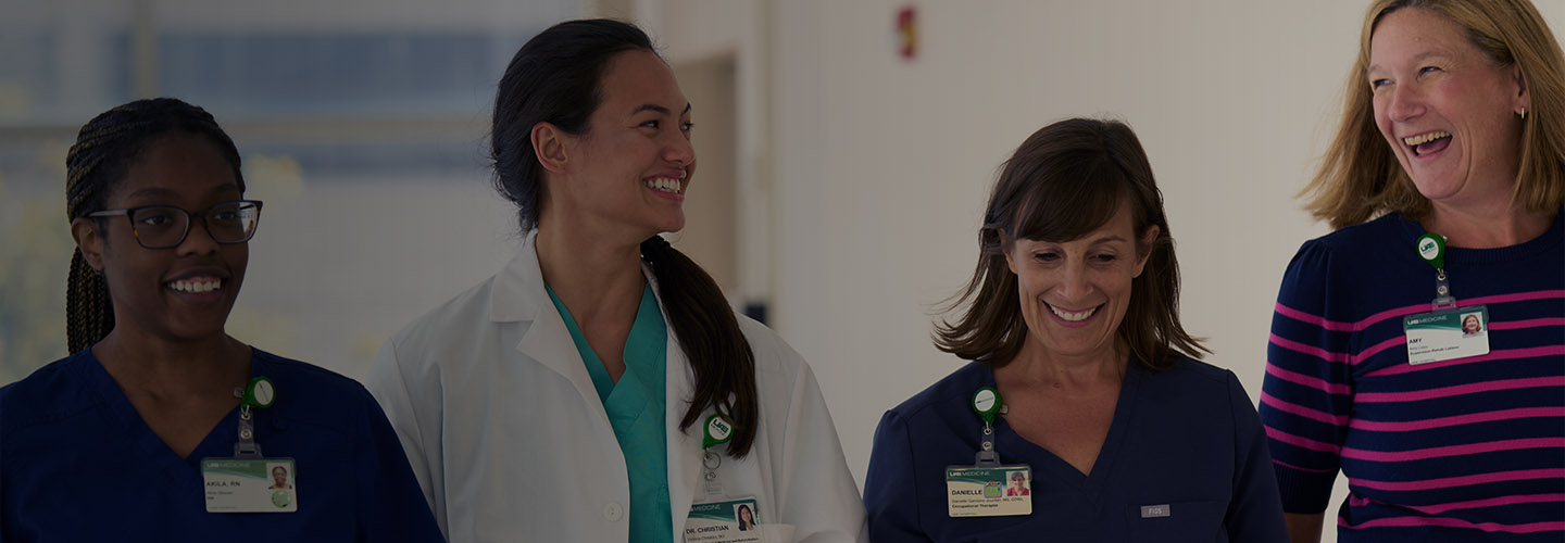 group of four female employees walking and smiling