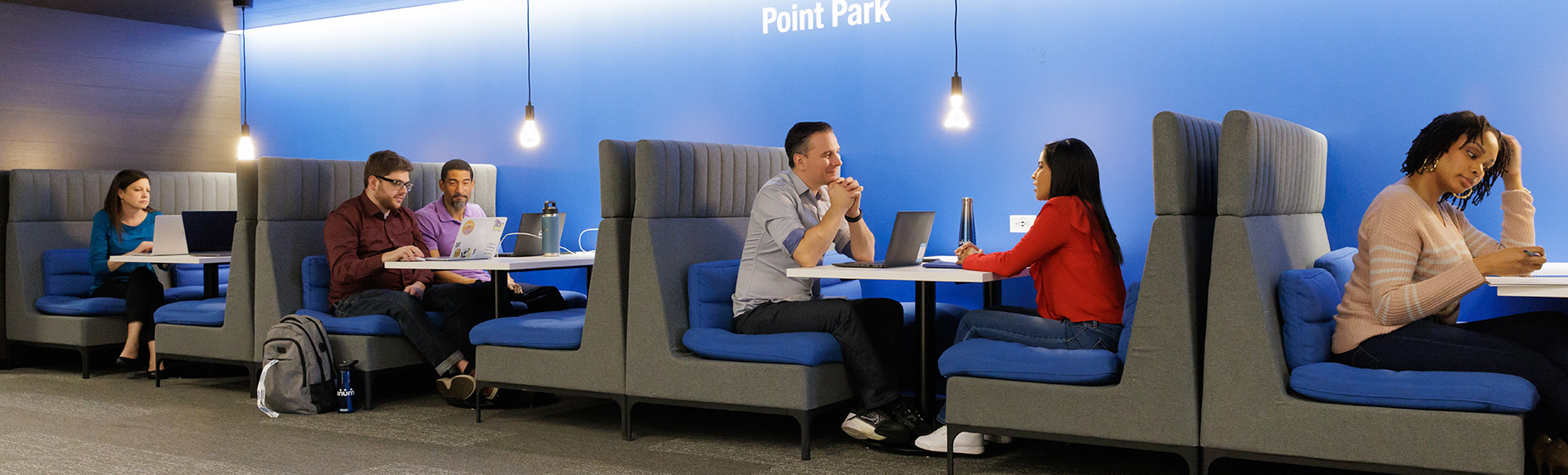 Several employees in an office environment sitting in booths working together