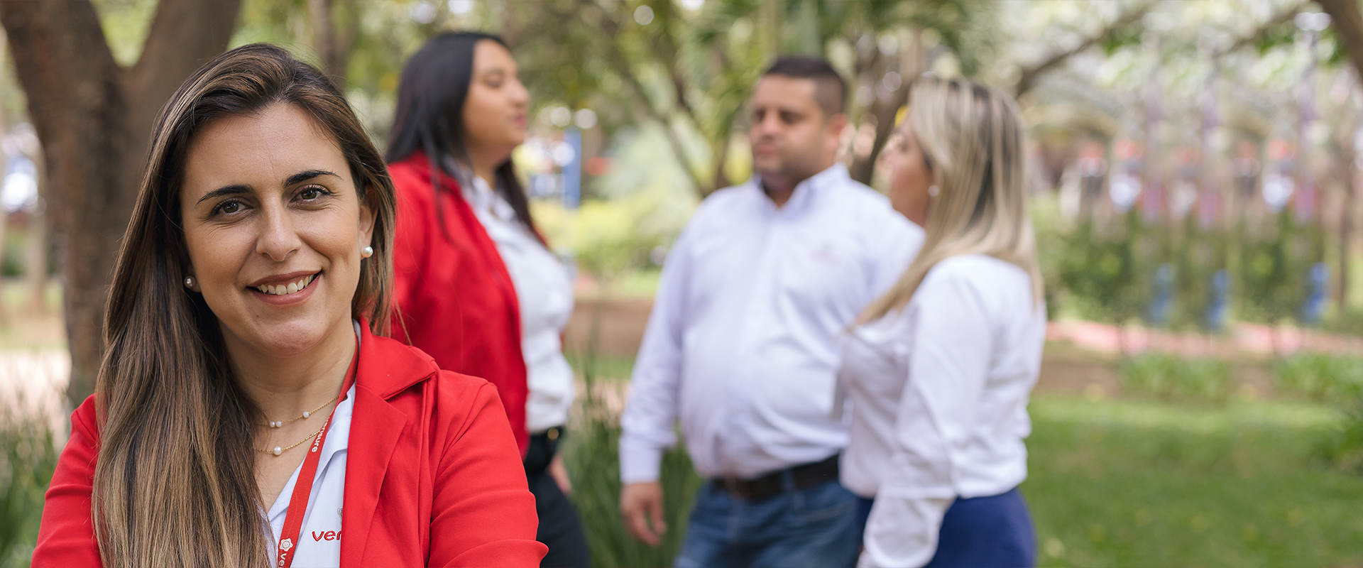 Chica de Verisure en exterior con compañeros de fondo.
