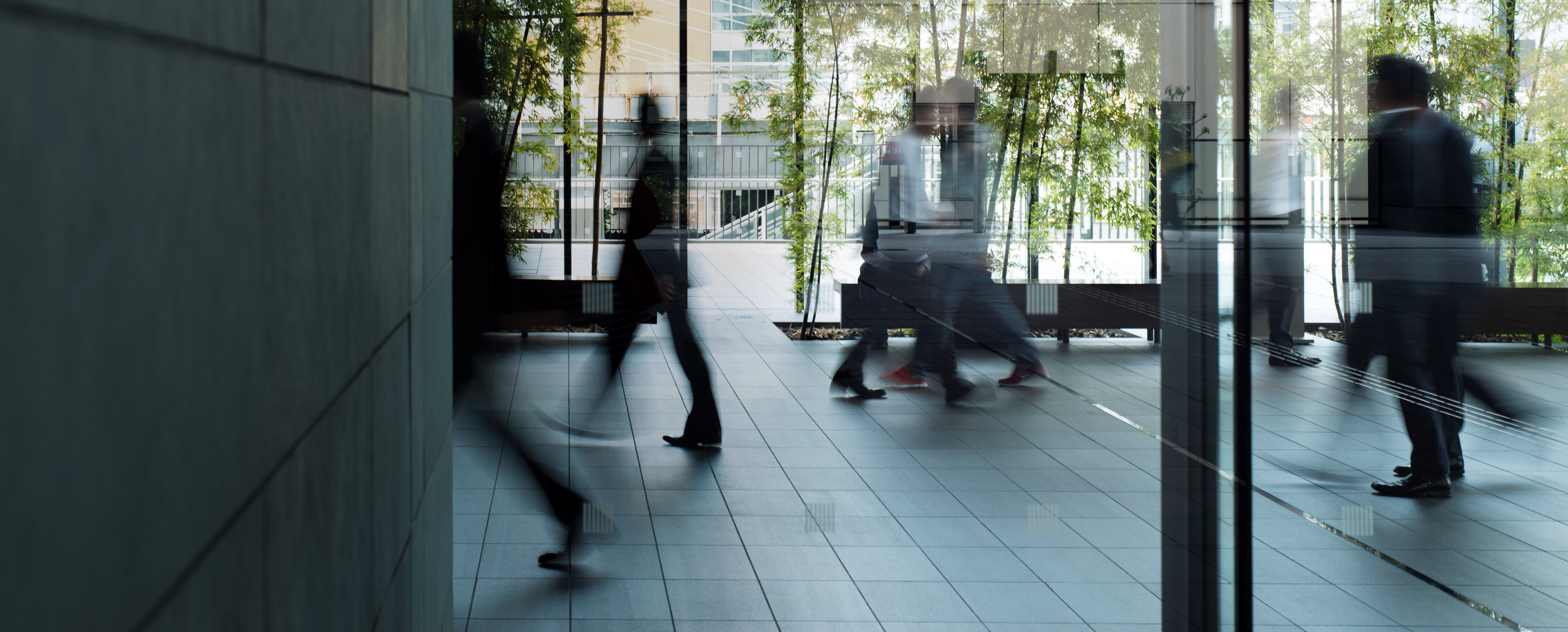 Office building, woman meets a coworker. Two men are walking by.