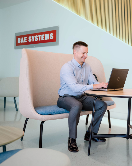 Tony, a program manager, works on his laptop in a BAE Systems lobby.