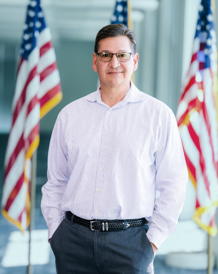 Richard, a factory manager and U.S. Air Force Veteran, stands with an American flag for a photo.