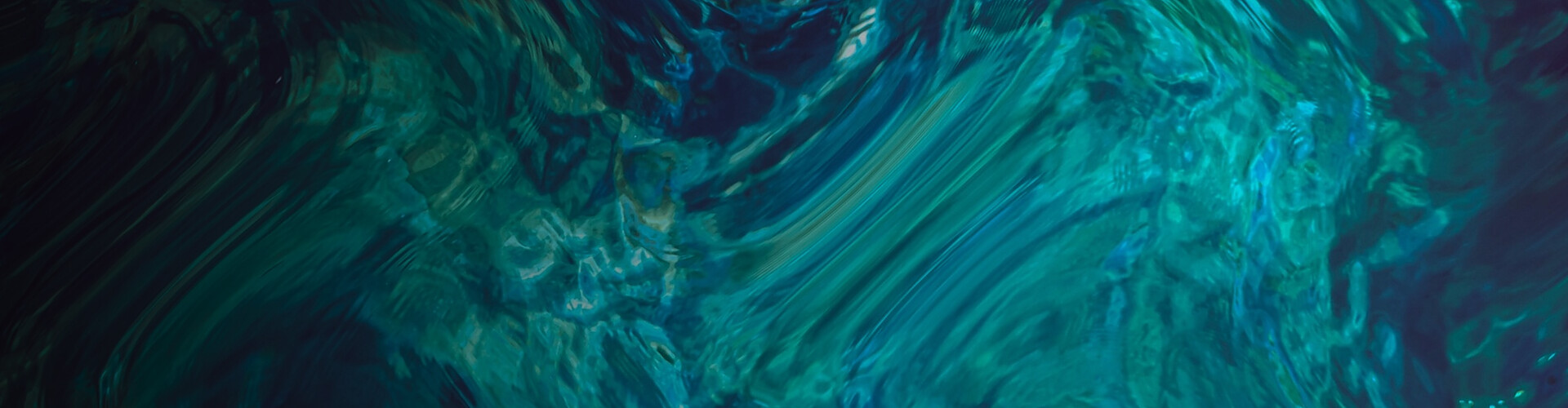 The image is a banner with a swirling pattern of dark and light blue hues, creating an abstract, watery effect. The colors blend seamlessly, giving a sense of fluidity and movement, reminiscent of ocean waves or flowing water. 