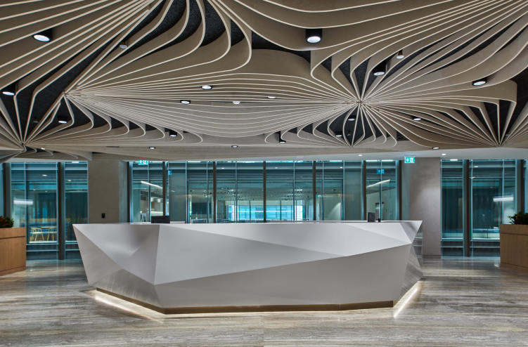 A modern reception area with an artistic white geometric desk and an intricate ceiling design featuring flowing patterns, located in a sleek office building.