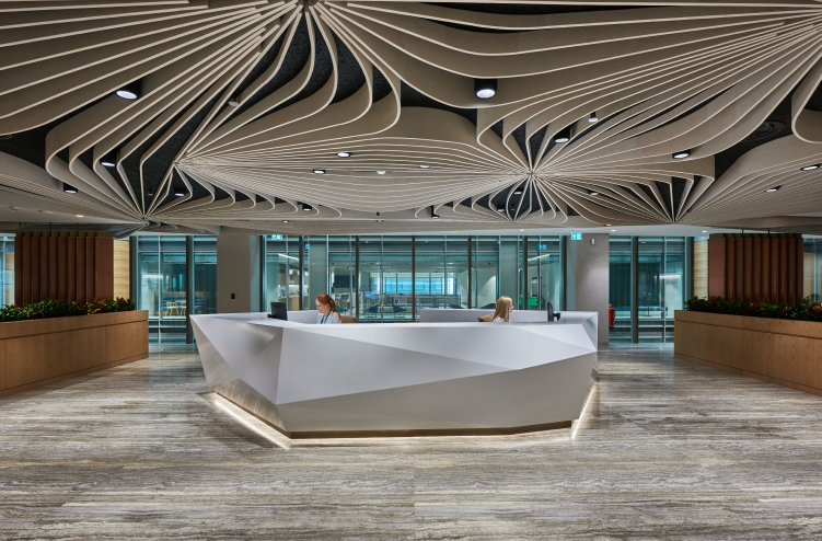 Another angle of the modern reception area with the geometric desk and flowing ceiling design, reflecting a cohesive and stylish office setting.