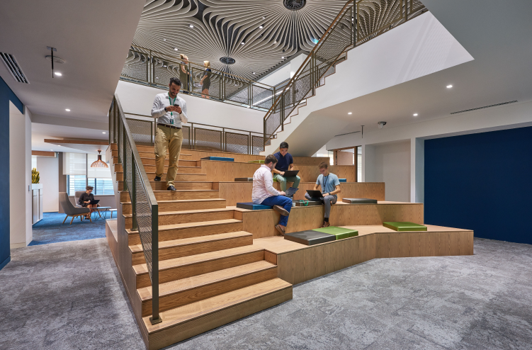 The same staircase area with people seated on the steps, fostering collaboration in a creative office environment.