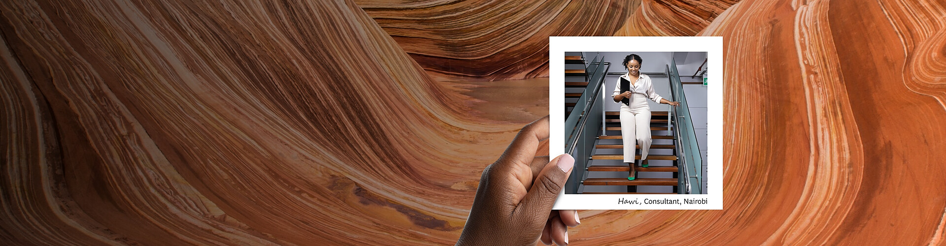 This panoramic banner shows a hand holding a photograph against a background of swirling sandstone formations. The photograph features Hawi, a consultant from Nairobi, walking down a staircase. She is dressed in professional white attire.