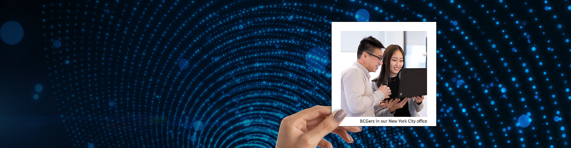 This panoramic banner shows a hand holding a photograph against a background featuring a dynamic blue digital dot matrix pattern. The photograph captures two colleagues, identified as BCGers from the New York City office, closely examining content on a laptop, engaged in a collaborative task. 