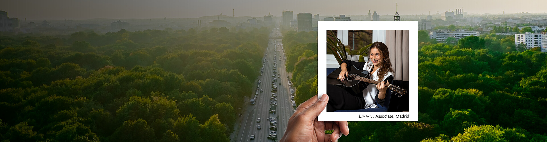 This panoramic banner image features a sprawling urban park with dense, lush greenery, extending into a cityscape in the distance, conveying a sense of tranquility amidst urban life. In the foreground, a hand is holding a photograph of Laura, an associate in Madrid, depicted in a relaxed office setting playing a guitar. 