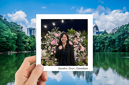 A hand holds a photo of four smiling people taking a selfie, with a vibrant city nightscape in the background.