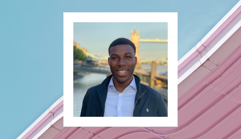 A portrait of a young man smiling warmly, standing in front of the iconic Tower Bridge in London during sunset. He is dressed casually in a black jacket over a white shirt, and the setting sun casts a soft golden light on his face. He is framed within a white square border against a stylized background featuring a blue sky and a pastel pink roofline.