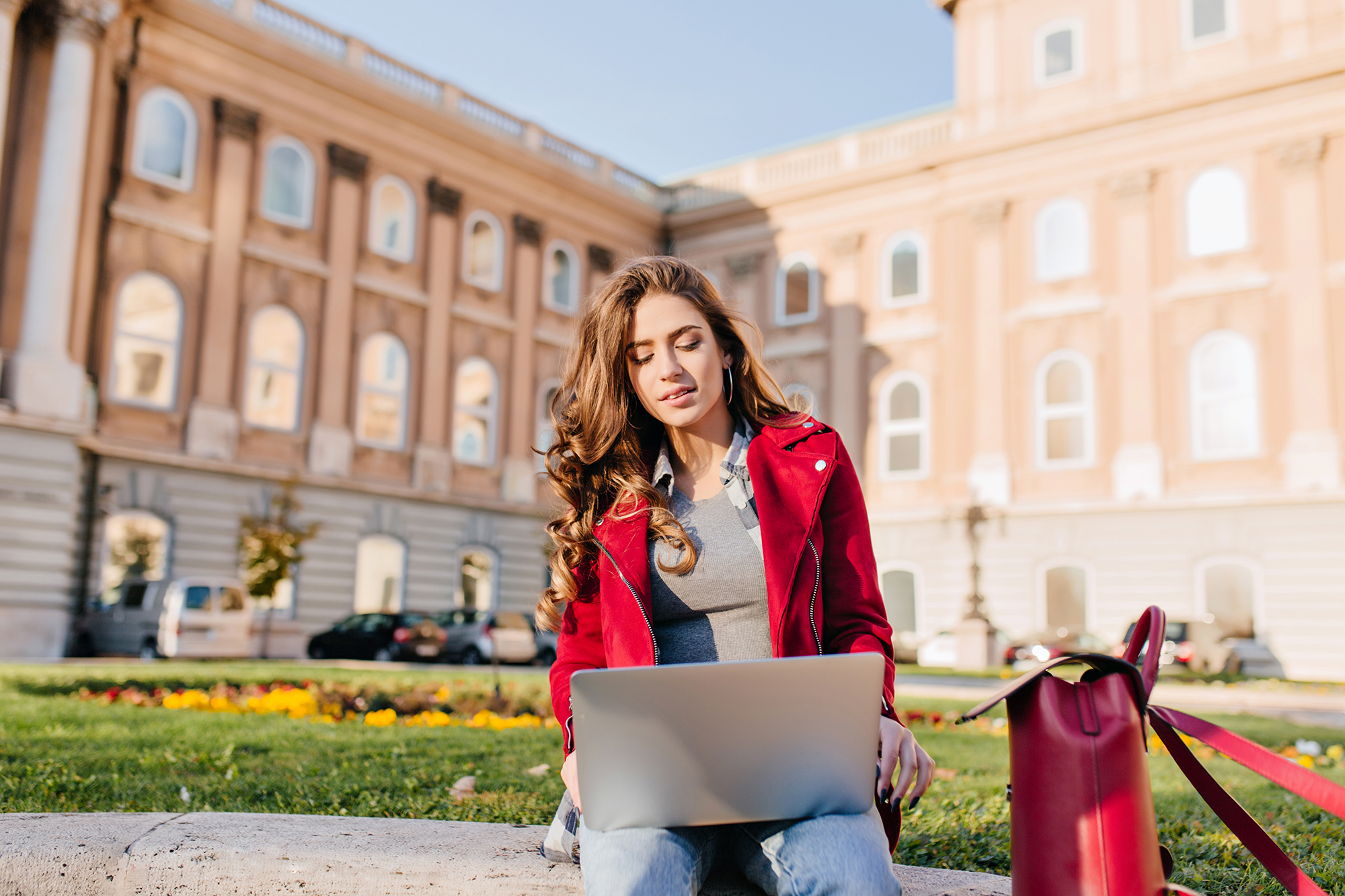 outdoor-portrait-serious-curly-female-student-sitting-with-laptop-ground