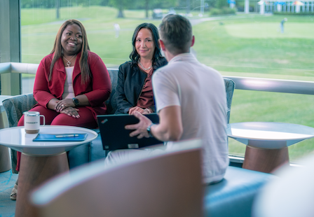 Three employees talking at a coffee table