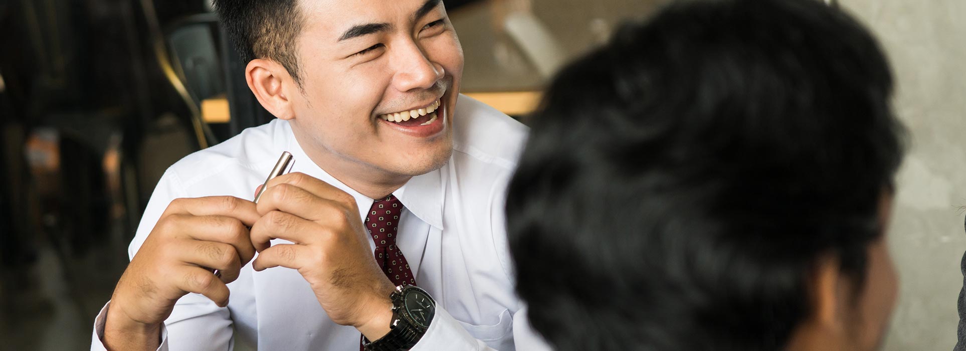 Man wearing a shirt and tie, laughing in an office setting