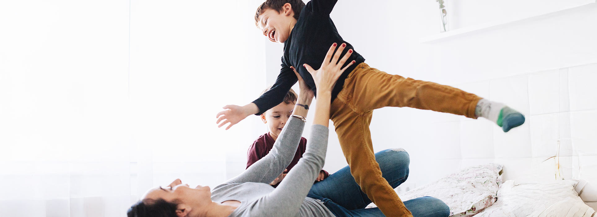 A mum playing with her two children who are laughing